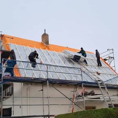 Handwerker bei Dacharbeiten auf einem Haus mit Gerüst