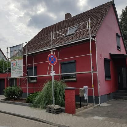 Rotes Wohngebäude mit Gerüst vor der Fassade