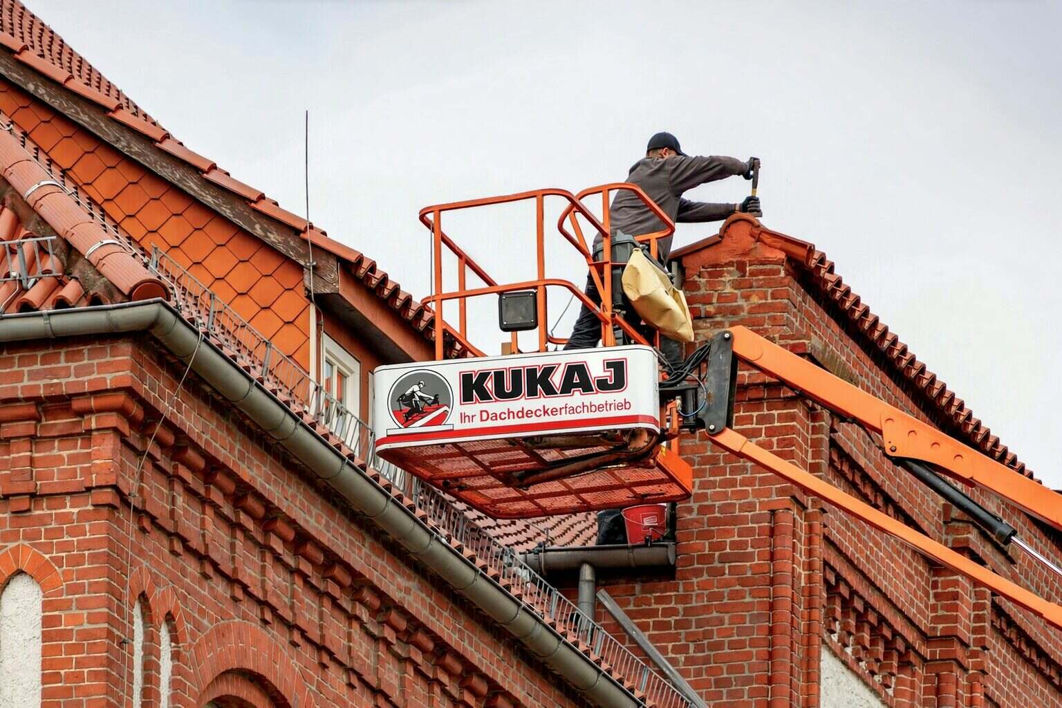 Dachdecker auf Hebebühne bei der Reparatur eines Schornsteins