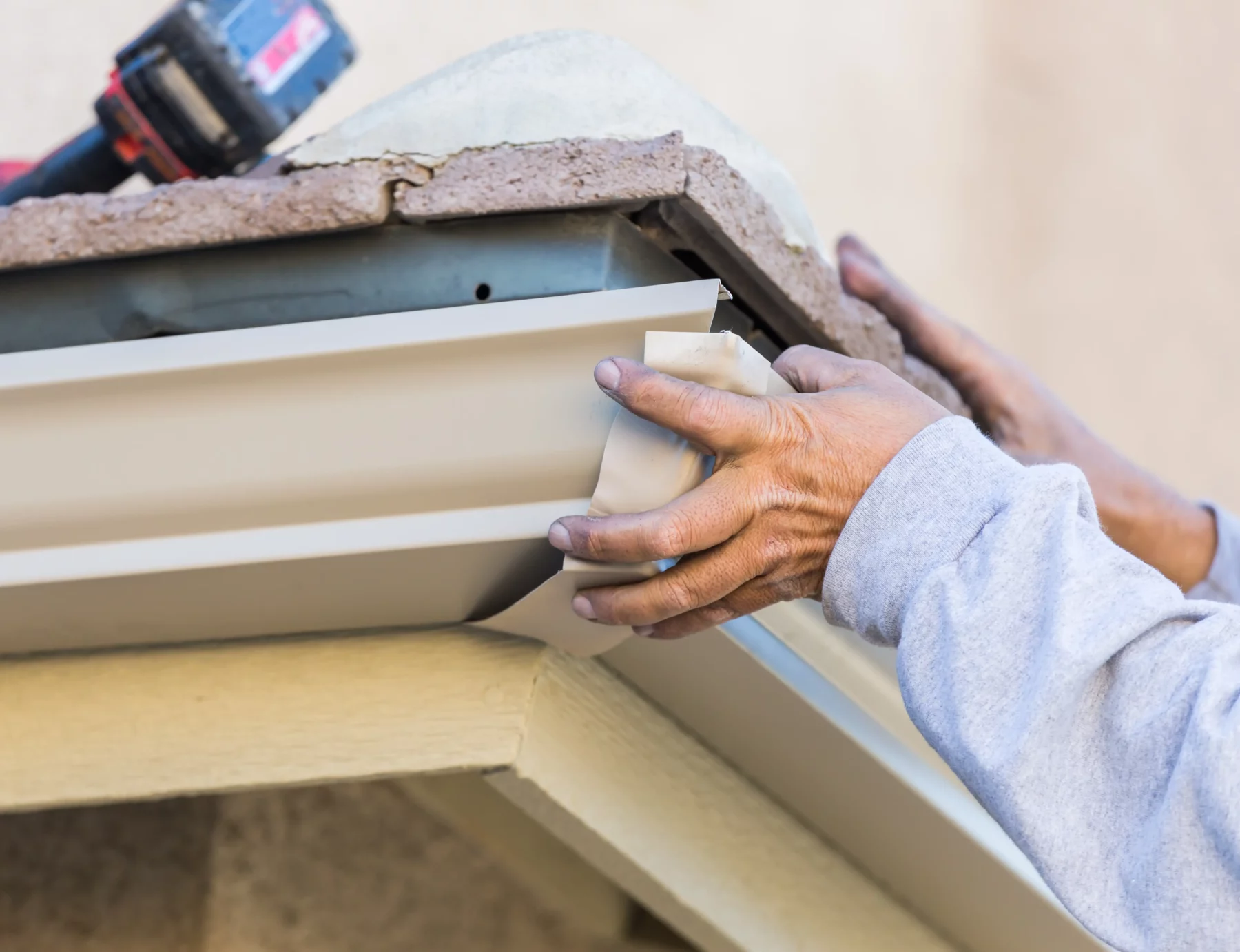 Handwerker befestigt eine Aluminium-Dachrinne an der Traufe