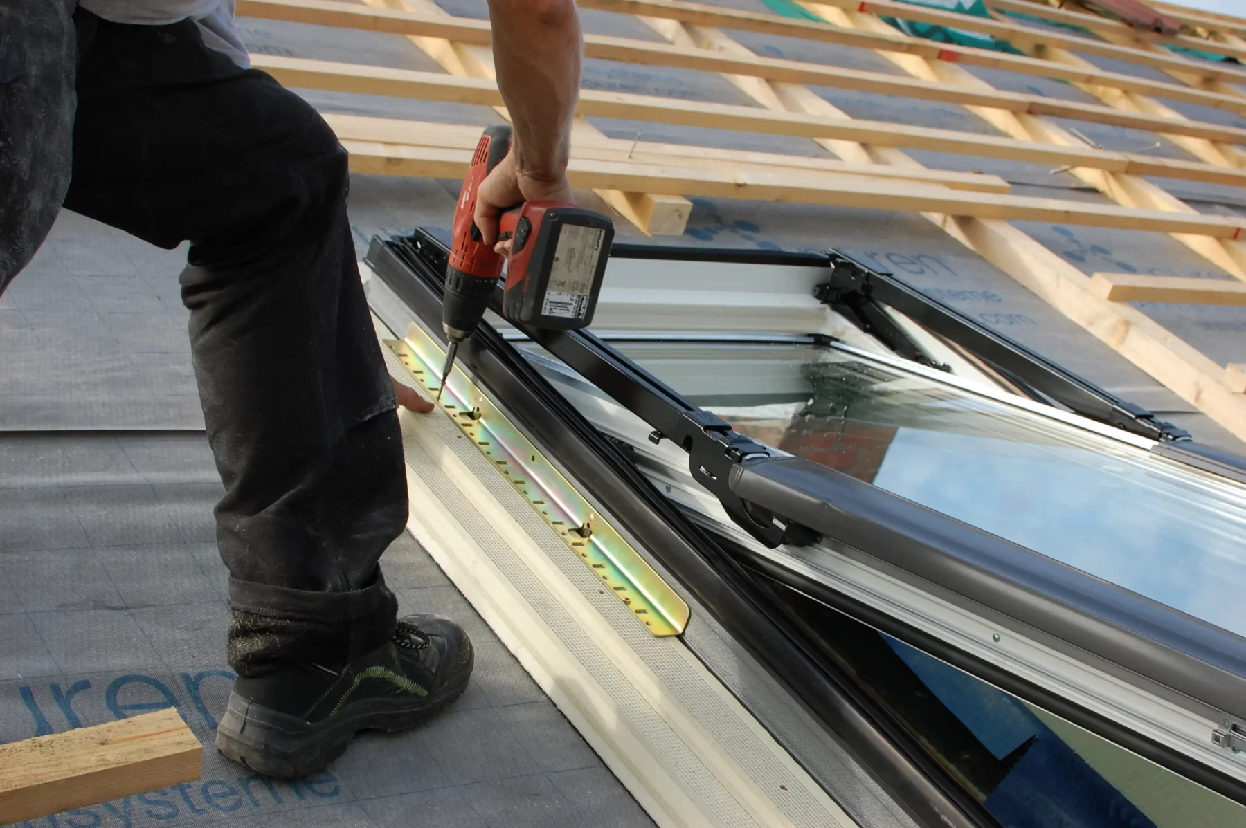 Handwerker montiert ein Dachfenster mit Schrauben auf dem Dach