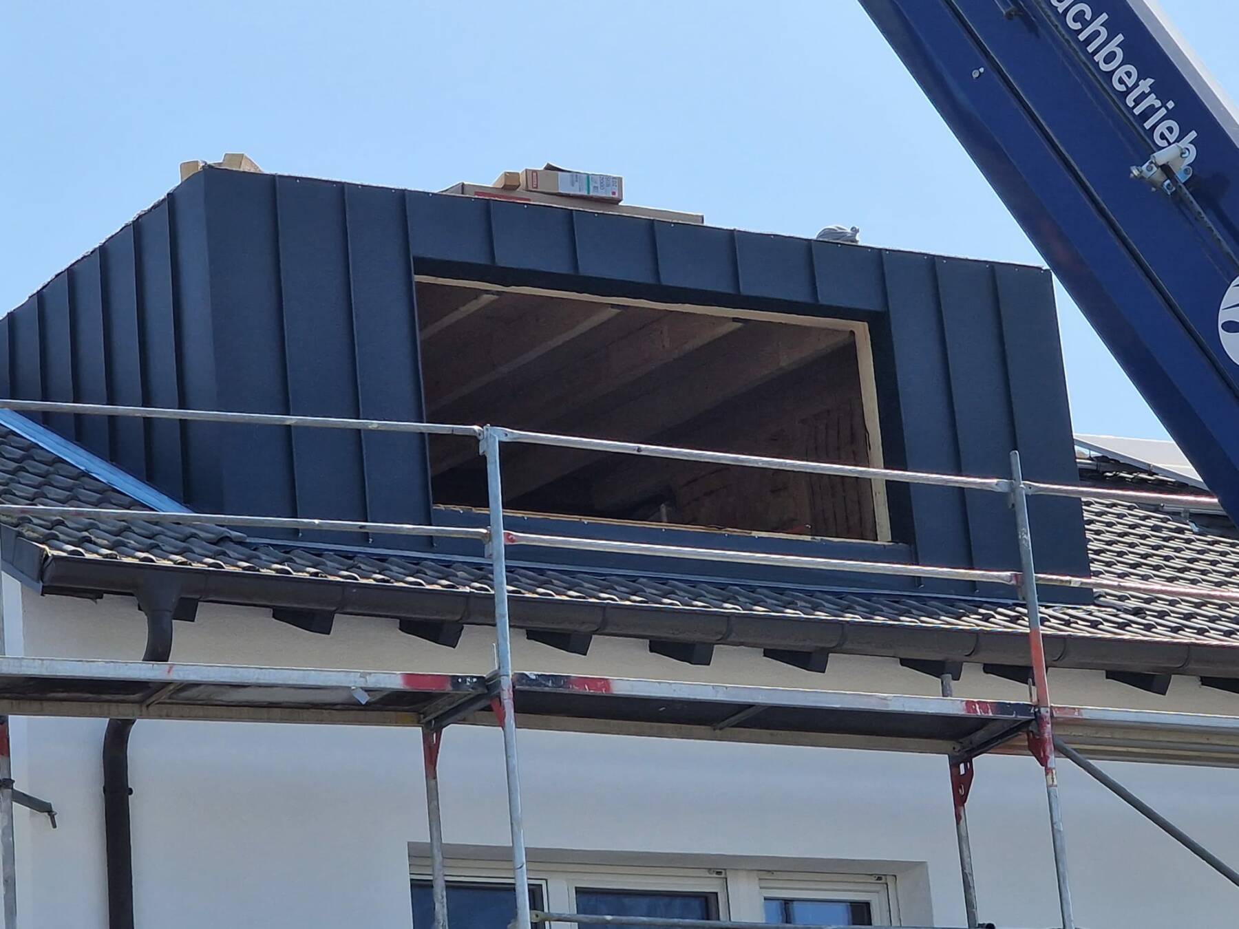 Solaranlage an einem Gebäude mit dunkler Dachfläche und Gerüst