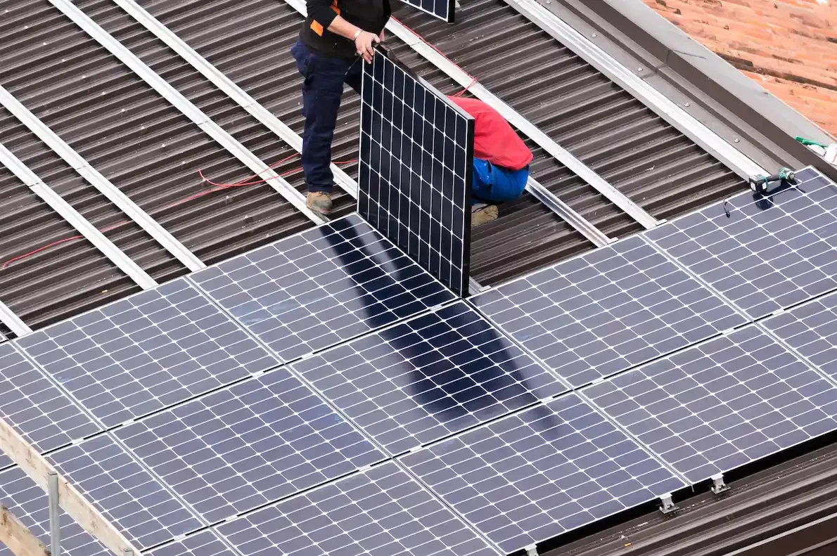 Handwerker bei der Montage von Solarmodulen auf einem Dach