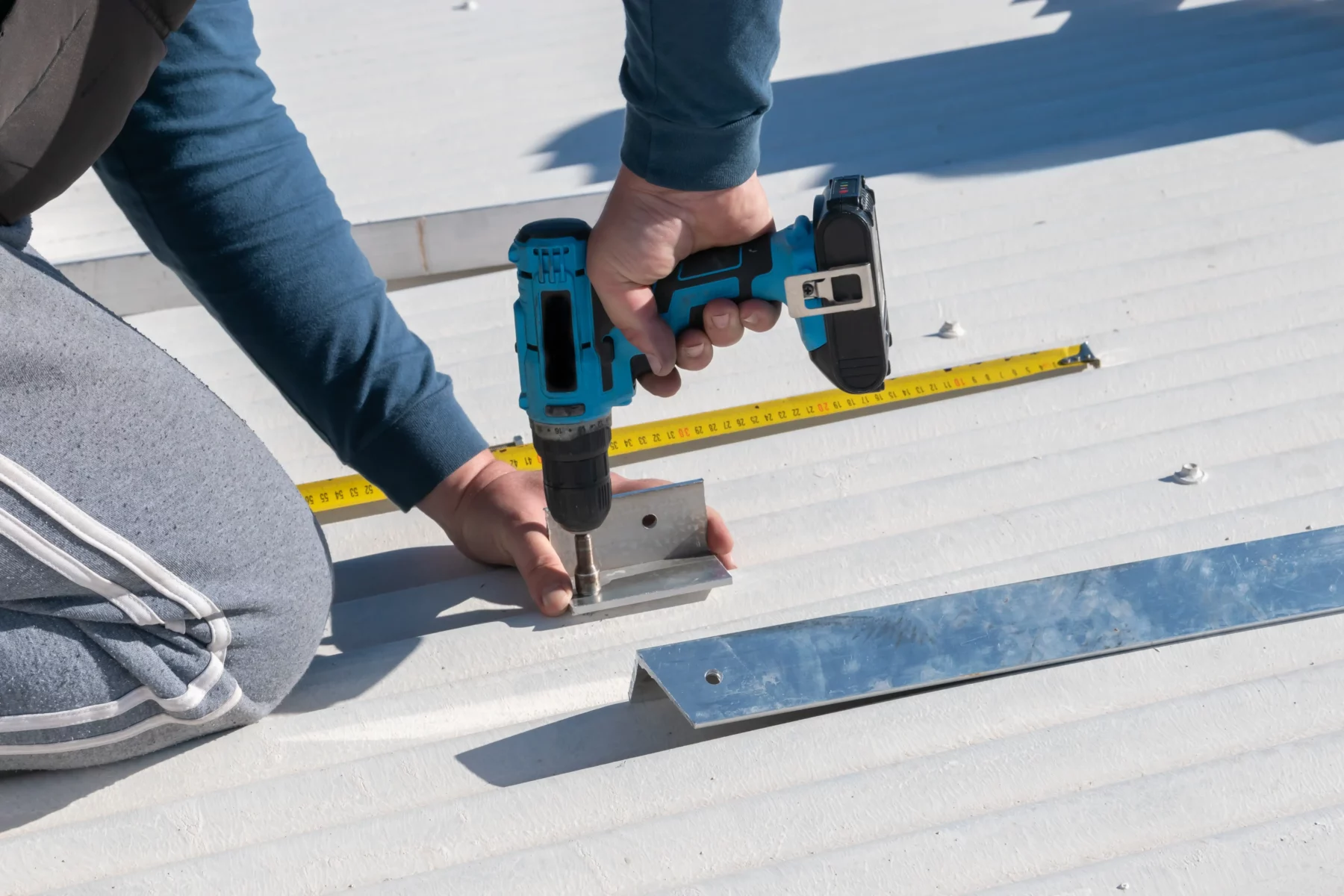 Handwerker bei der Montage einer Solaranlage mit Bohrmaschine auf dem Dach