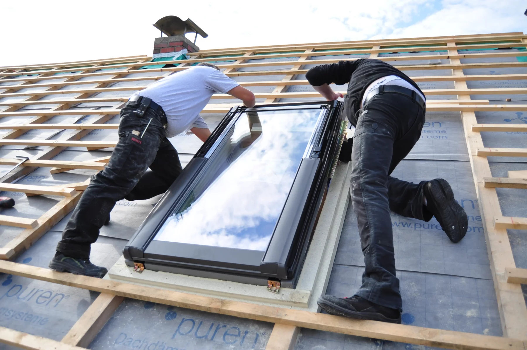 Zwei Handwerker bei der Montage eines Dachfensters